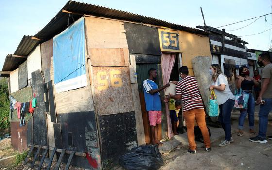 Residents in a poor section of Rio de Janeiro receive food and bread produced at the Sanctuary of Our Lady of Fatima during the COVID-19 pandemic. Volunteers delivered the bread June 24. (CNS/Reuters/Ricardo Moraes)